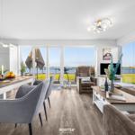 Wohn- und Essbereich mit Meerblick durch große Fenster und Balkon.