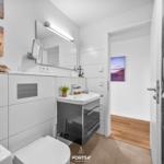 Badezimmer mit Waschbecken, Spiegel und Heizung. Wandbild zeigt Strand.