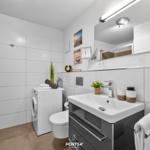 Badezimmer mit Dusche, Waschmaschine und Waschtisch