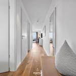 Flur mit Holzboden, weißen Wänden und Sitzbank mit Kissen.