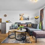 Wohnung mit Essbereich, Sofa, Couchtisch und Blick auf Balkon.