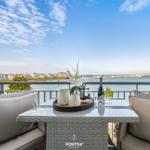 Terrasse mit Tisch und Stühlen, Blick auf Wasser und Häuser
