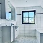 Badezimmer mit Waschbecken, Badewanne und Fenster