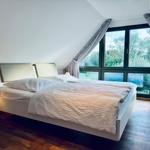 Schlafzimmer mit Doppelbett, großem Fenster und Holzboden.