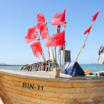 Holzboot mit roten Flaggen am Strand
