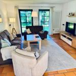 Wohnzimmer mit Sofa, Sessel, Couchtisch und Fernseher.