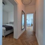 Flur mit H Stockboden, Spiegel und Schlafzimmer im Hintergrund.