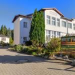 Weiße Ferienhausanlage mit gepflastertem Weg und Garten. Schild mit Informationen.