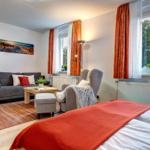 Ein Schlafzimmer mit Sofa, Sessel und großem Fenster mit Blick auf Bäume.