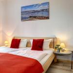 Schlafzimmer mit Doppelbett, roter Decke und Wandbild an der Wand.