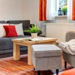 Ein Wohnzimmer mit Sofa, Sessel und Tisch. Auf dem Tisch steht eine Pflanze.