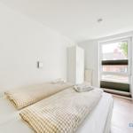 Schlafzimmer mit Bett, Kleiderschrank und Fenster. Bett mit kariertem Bettzeug.