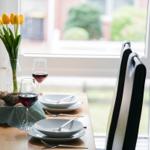 Tisch gedeckt mit Wein, Brot und Tulpen vor Fenster