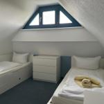 Zimmer mit zwei Einzelbetten, Schrank und Dachfenster.