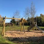 Kinder-Spielplatz mit Schaukel und Rutsche auf Sandfläche im Garten