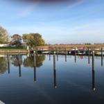 Hafen mit Stegen und Booten an ruhigem Wasser unter blauem Himmel.