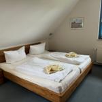 Doppelbettzimmer mit Holzbett, Fenster und Wandbild.