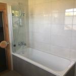 Bad mit Badewanne und Duschkabine, weiße Fliesen, Holztür