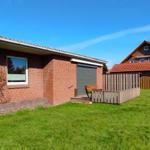 Rotes Backsteinhaus mit Garten und Terrasse. Im Hintergrund ein weiteres Haus mit Solaranlage.