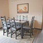 Esszimmer mit Tisch, sechs Stühlen und Wandbild.