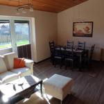 Wohn- und Essbereich mit Sofa, Tisch und Fenster zur Außenterrasse.