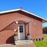 Rotes Backsteinhaus mit weißer Tür und gepflastertem Weg.