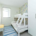 Zimmer mit Doppelstockbett, Fenster und Kleiderschrank.