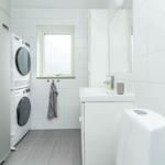 Badezimmer mit Waschmaschine, Spülmaschine und Toilette.