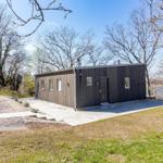 Moderne Holzhütte mit Terrasse und Blick auf Wasser.