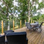 Terrasse mit Sitzgruppe und Esstisch unter Bäumen.