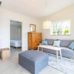 Wohnzimmer mit Sofa, Couchtisch und Kaminofen. Durchgang zur Schlafzimmer.