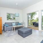 Wohnbereich mit Sofa, Couchtisch und Terrasse mit Blick auf Grünflächen.