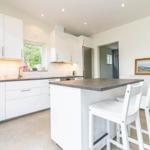 Moderne Küche mit weißen Schränken und Kücheninsel mit Sitzhöhe.