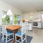 Küche und Essbereich mit Holztisch, weißen Stühlen und Blick auf die Terrasse.