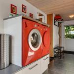 Laundry room with red washing machine and dryer, gray floor, and wooden ceiling.