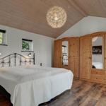 Bedroom with wooden floor, wooden ceiling, and large wardrobe with mirrors.