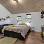Bedroom with wooden ceiling, bed, dresser, and windows.