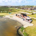Strand mit Bootssteg, Strandkörben und Ferienhäusern am Ufer