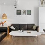 Wohnzimmer mit Ledersofa, weißem Tisch und Wandbildern.