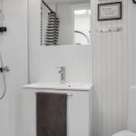 Badezimmer mit Dusche, Waschbecken und Toilette. Weiße Wände und ein brauner Handtuch.