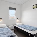 Zwei Einzelbetten mit blauen Bettwäsche, Nachttisch und Fenster.