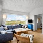 Wohnzimmer mit Sofa, Tisch und Blick auf Dünen.