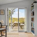 Raum mit Schiebetür zu Terrasse, Bücherregal und Wandinstrument.