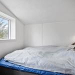 Schlafzimmer mit Bett, Fenster und Wandlampe