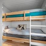 Ein Schlafzimmer mit einem Doppelstockbett aus Holz und einer weißen Leiter.