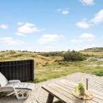 Terrasse mit Liegestuhl und Tisch. Blick auf Dünen und Himmel.
