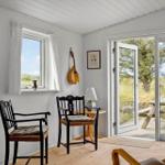 Raum mit Stühlen, Fenster und Tür zu einem Außenbereich mit Tisch.