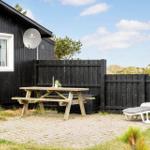 Außenbereich mit Tisch, Liegestuhl und Holzhaus. Hinterhof mit Zaun und Strandblick.