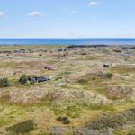 Ausblick auf Dünenlandschaft mit Häusern und Meer im Hintergrund.