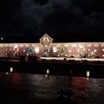 Festlich beleuchtetes Gebäude mit Weihnachtsdekoration und Adventskalender an der Fassade.